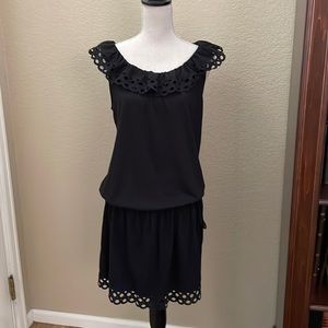Short black dress with detailed collar and hem.